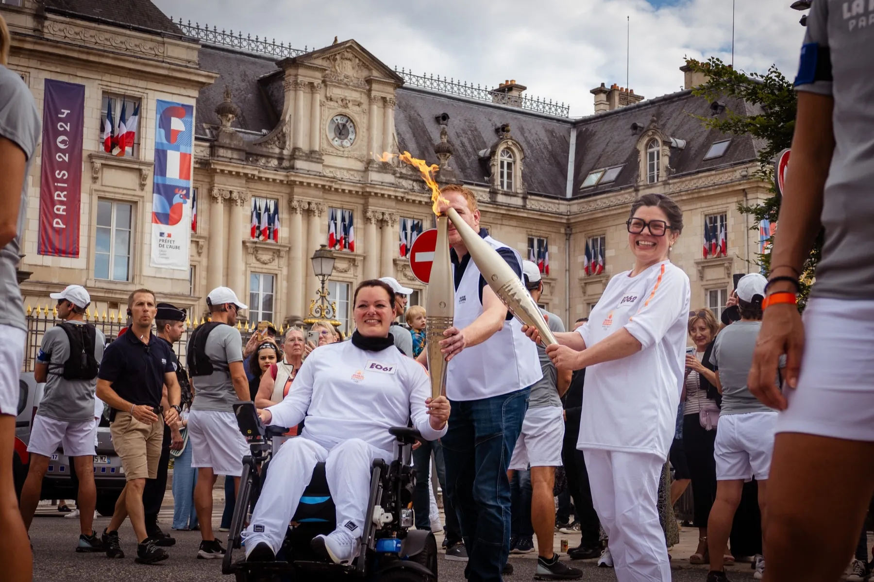 Relais de la flamme olympique Paris 2024 : porteurs de torche entourés de spectateurs