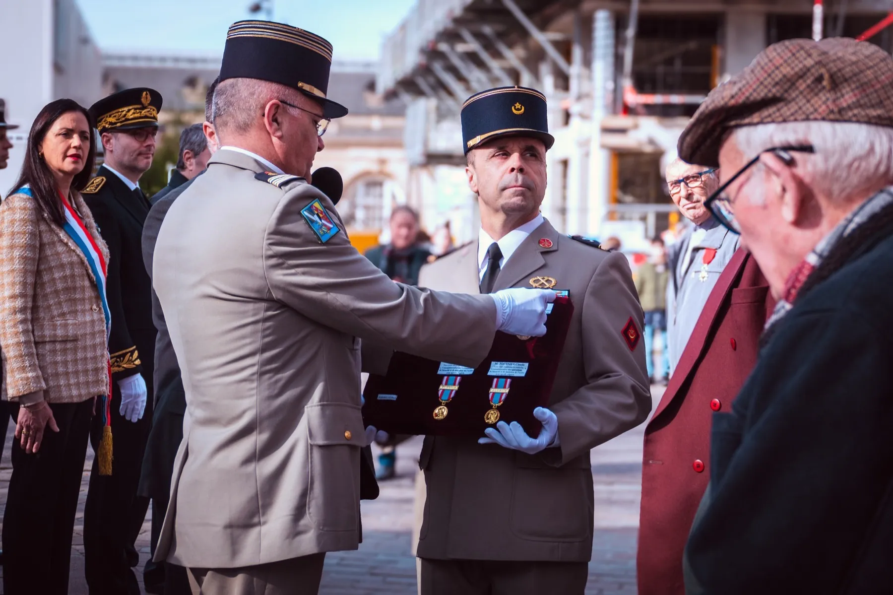 Cérémonie de remise de décorations : militaires en uniforme, élue en écharpe tricolore et homme âgé