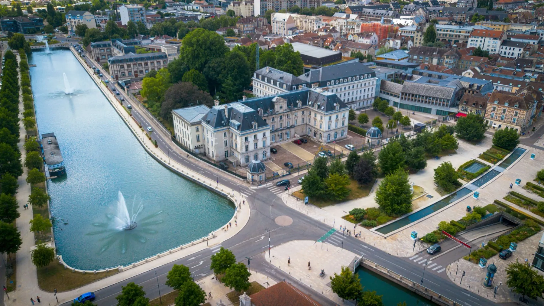Vue aérienne par drone d'un bassin avec jet d'eau au cœur d'une ville