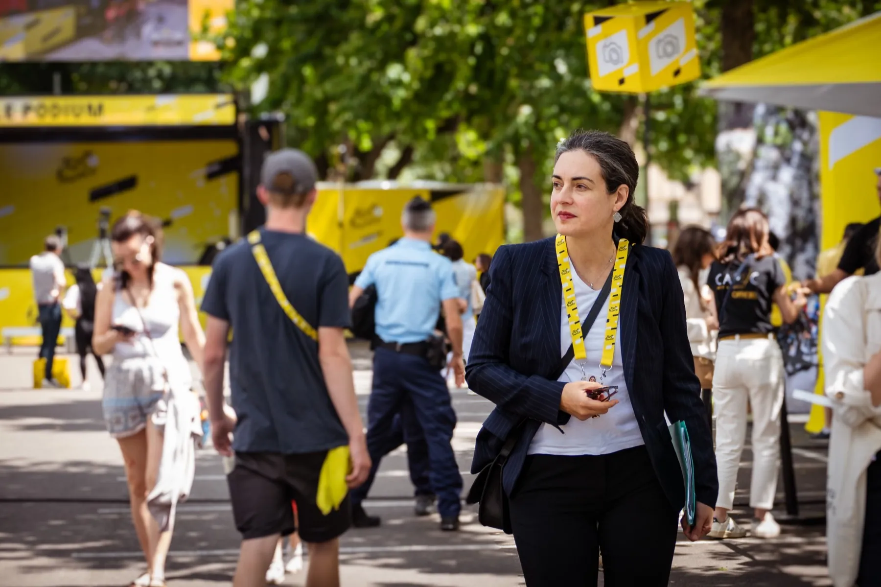Femme avec un badge jaune marchant dans la foule d'un événement sportif en plein air