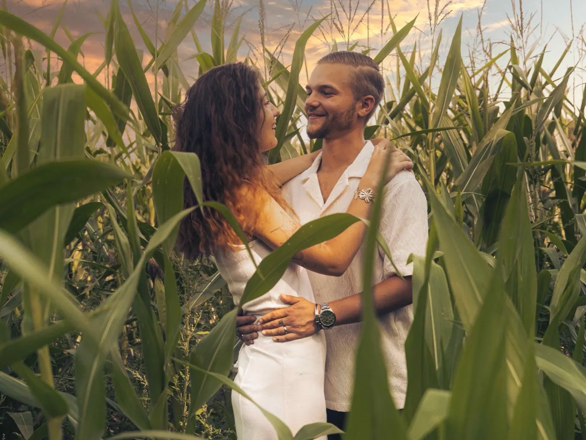 Couple enlacé dans un champ de maïs au coucher du soleil